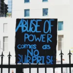 protest sign: abuse of power comes as no surprise